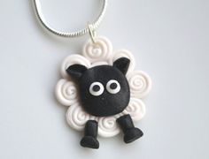 a black and white sheep is hanging from a silver chain