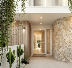 the entrance to a modern home with cactus and succulents growing on the wall