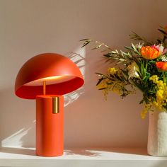 an orange table lamp next to a vase with flowers