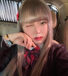 a woman with long hair wearing a red and black bow tie sitting in a car