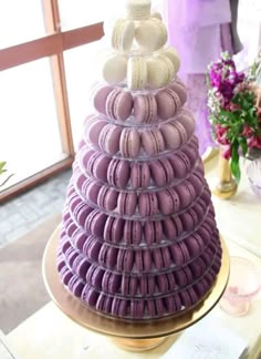 a purple and white cake with macaroons stacked on it's sides in front of a window