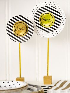 two black and white striped paper plates with gold foil lettering on them sitting on a table