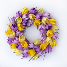 a wreath made out of purple, yellow and white paper flowers on a white background