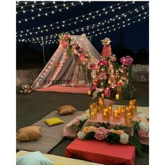 a table with candles and flowers on it in the middle of a courtyard at night