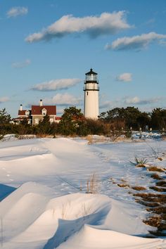 a snow covered field with a light house in the background