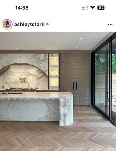 a large kitchen with marble counter tops and an oven in the center, surrounded by glass doors