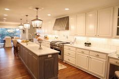 a large kitchen with white cabinets and wood floors