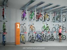 a woman is standing in front of a rack with bicycles hanging from it's ceiling