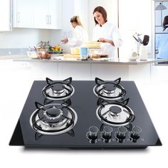 two women in the kitchen preparing food on an electric burner cooktop with pots and pans