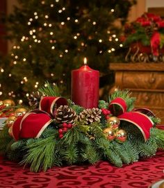 there is a candle on the table next to some cups and saucers in front of a christmas tree