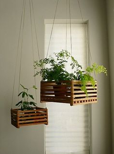 three wooden planters hanging from strings in front of a window with plants growing out of them