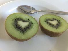 two kiwi halves on a white plate with a spoon