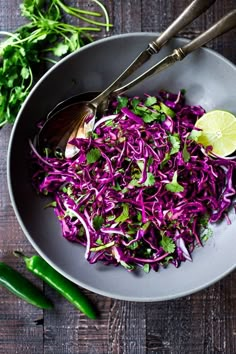 a bowl filled with coleslaw and lime wedges on top of a wooden table