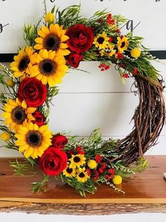 a wreath with sunflowers, roses and greenery sits on a wooden table