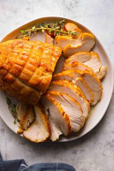 a white plate topped with sliced chicken and potatoes on top of a table next to a pair of blue jeans