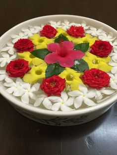 a white bowl filled with flowers on top of a wooden table