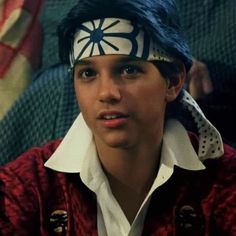 a young man wearing a bandana and headband in front of an american flag