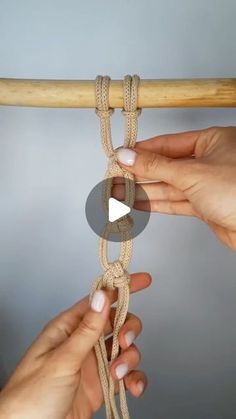 two hands holding onto a rope that is attached to a wooden pole with another hand