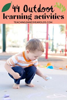 a toddler playing with chalk on the ground in front of an outdoor learning area