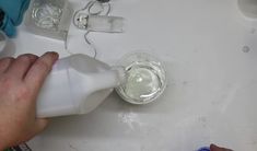 a person is pouring water into a cup on a sink with other items around it