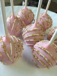 pink and white cake pops with gold sprinkles on a plate, ready to be eaten