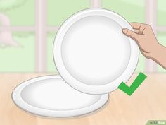 a white plate being held up by a person's hand with the green arrow pointing to it