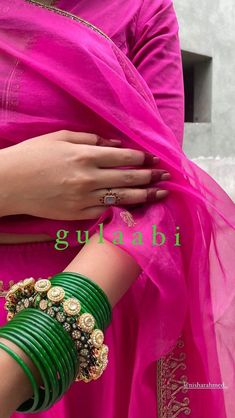 a woman in a pink sari and green bracelets is holding onto her hand