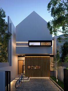 a bike is parked in front of a modern house at dusk with its lights on