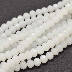 white glass beads are lined up on a black surface