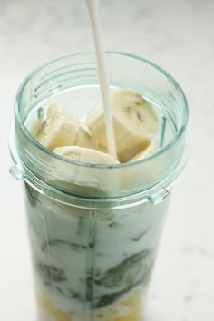 a glass jar filled with sliced bananas on top of a white counter next to a spoon