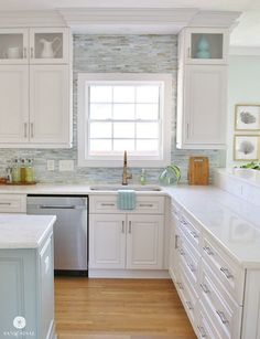 a clean kitchen with white cabinets and stainless steel dishwasher in the center island