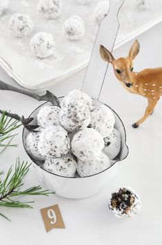 a small deer figurine next to a bowl of snowballs