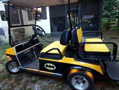 a yellow and black golf cart parked in front of a building with the door open