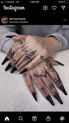 a woman's hand with black nails and tattoos on it