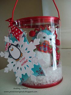 a red bucket filled with snow and a penguin