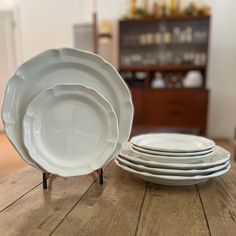 a stack of white plates sitting on top of a wooden table next to each other