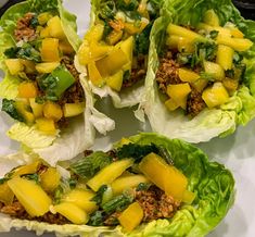 four lettuce cups filled with different types of food on top of a white plate