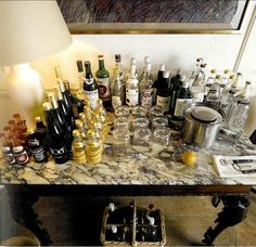 a table full of bottles and glasses on top of a tiled floor next to a wall