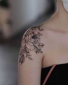 a woman with a black and white flower tattoo on her shoulder is looking at the camera