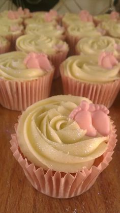 cupcakes with frosting and pink icing on a wooden table in rows