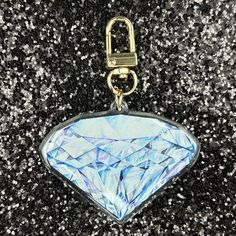 a blue diamond shaped keychain hanging on a black and white background with silver speckles