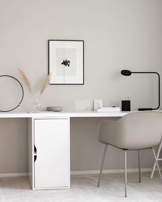 a white desk with two chairs and a framed photograph on the wall above it in a room