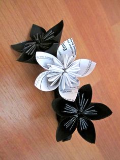 three black and white paper flowers sitting on top of a wooden table next to each other