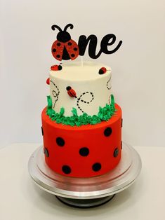 a cake decorated with ladybugs and the word one on top