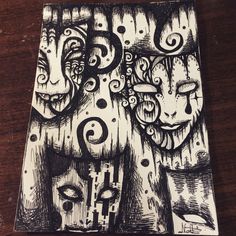 a black and white drawing of two faces on a wooden table with circles around them