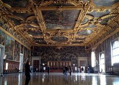 an ornate room with paintings on the ceiling and people walking around it in front of them