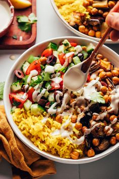 two bowls filled with rice, beans and vegetables being drizzled with dressing