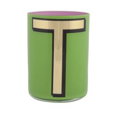 a green candle with a gold cross on the front and purple inside, sitting on a white surface