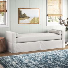 a white couch sitting in a living room next to a rug on top of a wooden floor