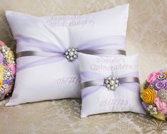 two pillows with flowers on them sitting next to each other in front of a wall